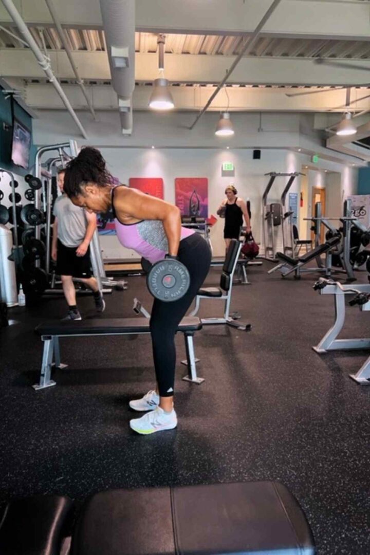 woman raising barbell in barbell row exercise