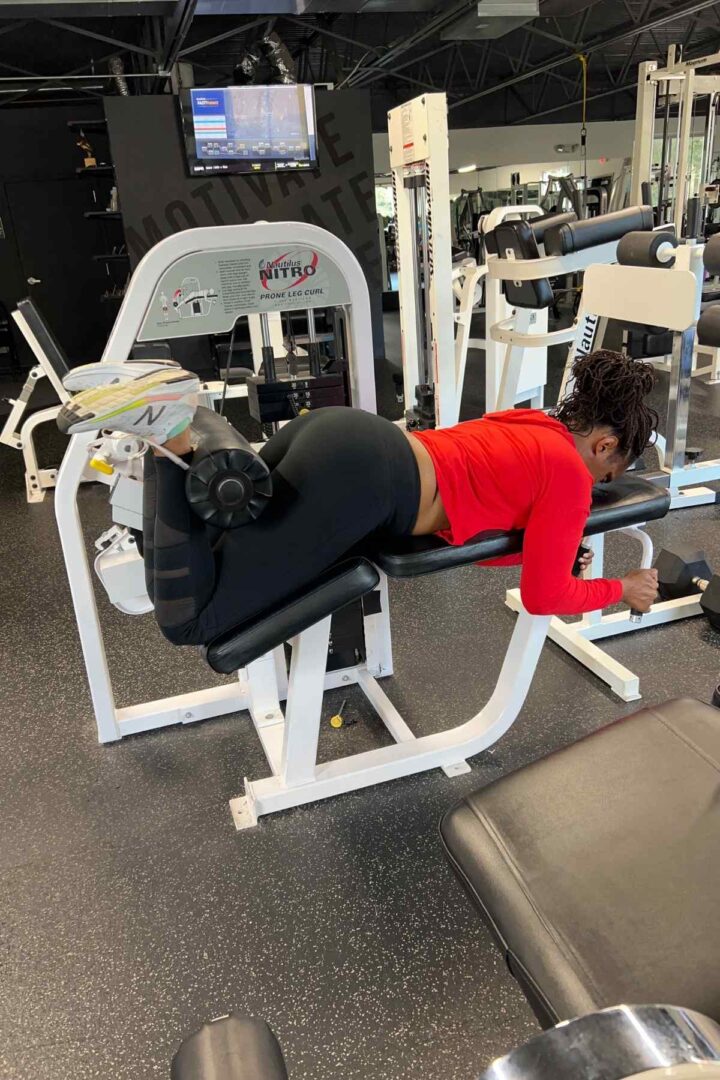 woman doing traditional leg curls in red shirt and black leggings