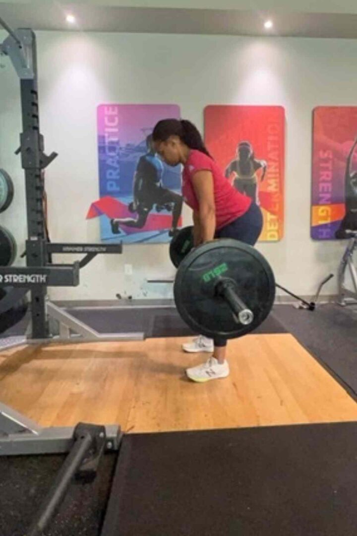 woman in red shirt doing barbell dealifts