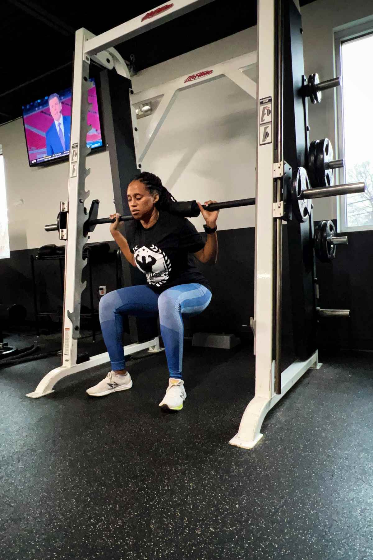 woman doing smith machine squats in blue leggings
