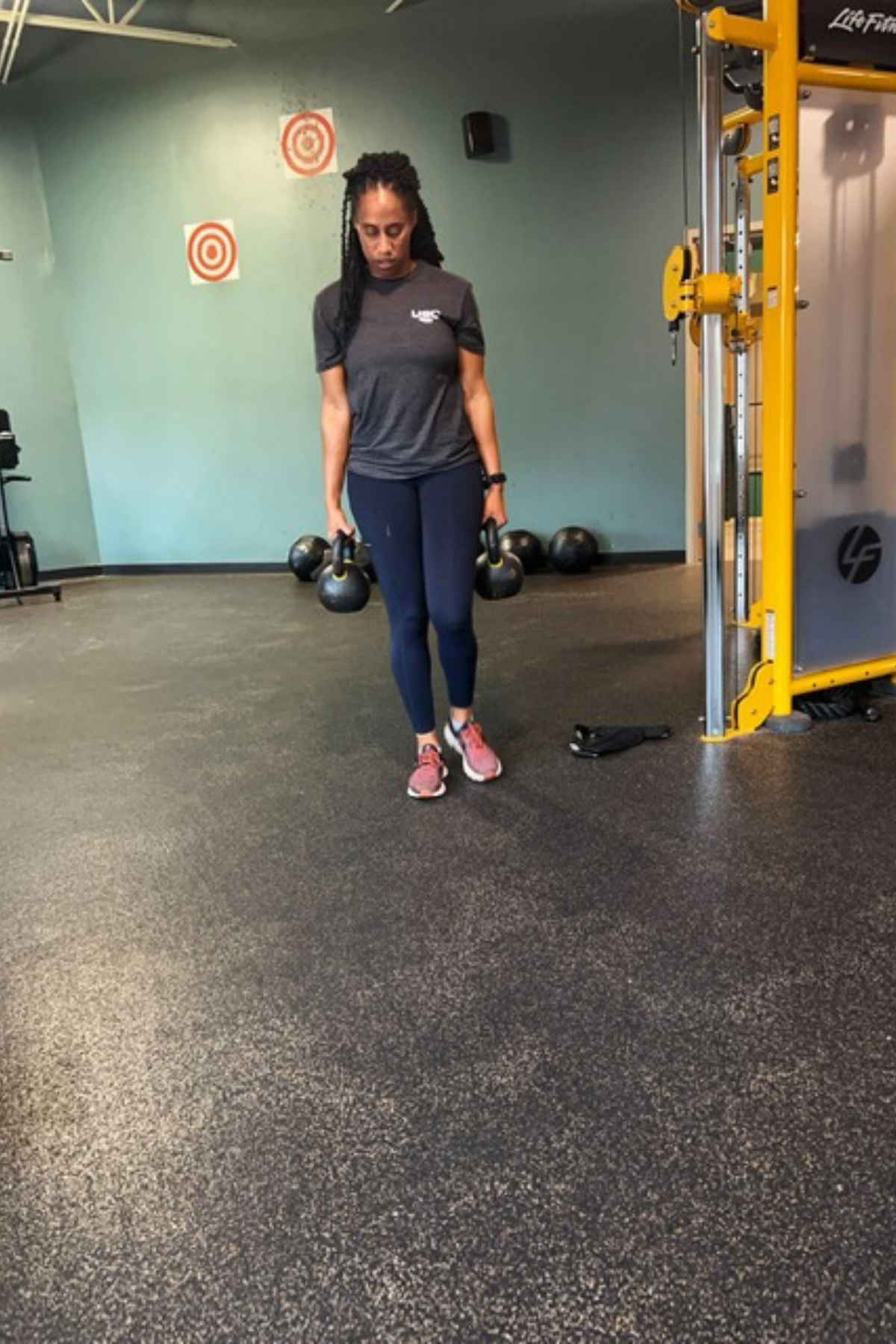 woman walking with two heavy dumbbells for a loaded carry compound movement