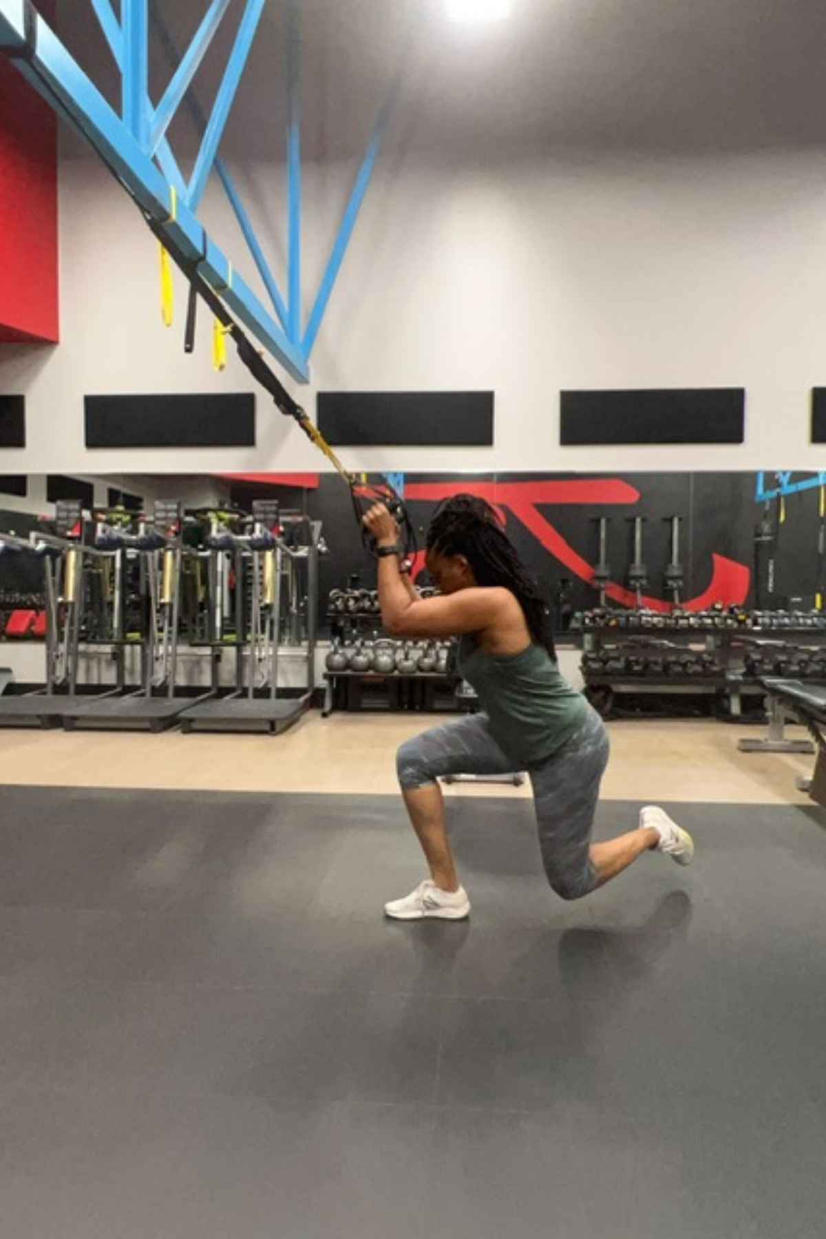 woman holding trx handles lowered in the the TRX curtsy lunge