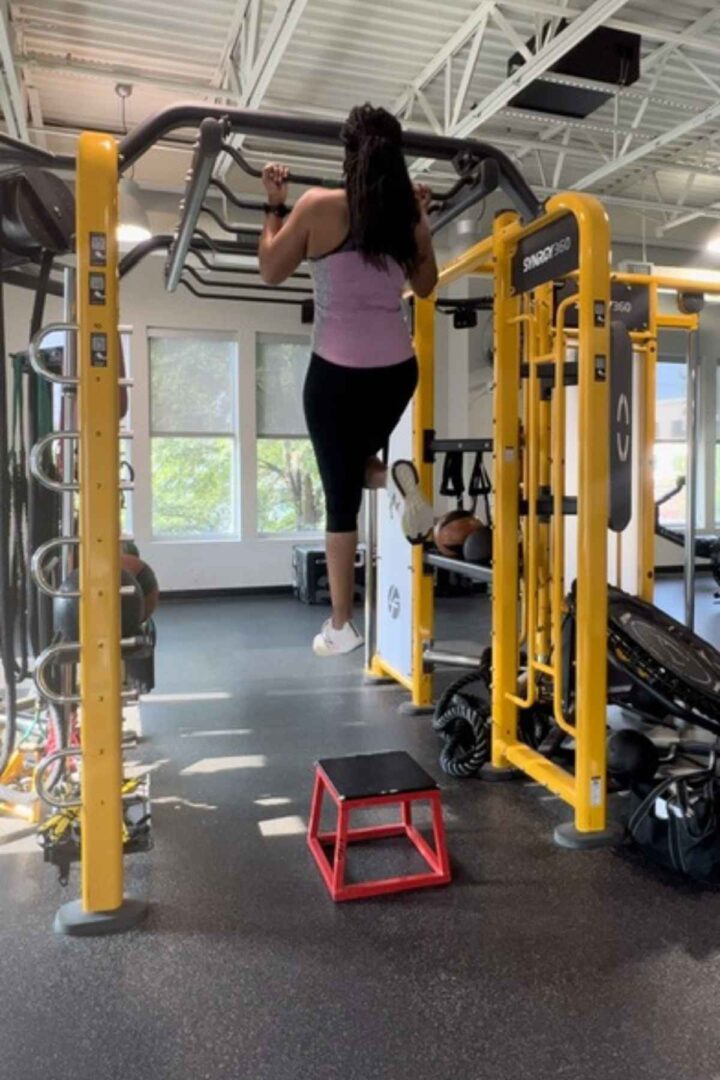 woman doing assisted chin ups in the gym with a resistance band