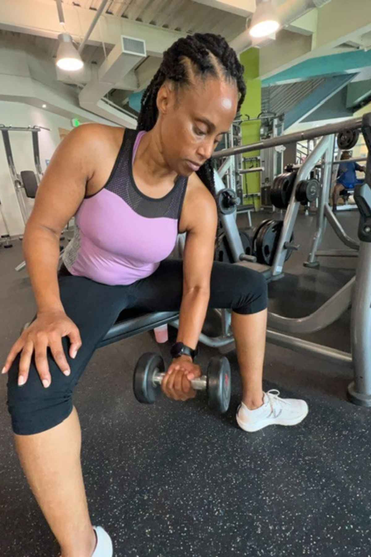 woman doing concentration curls at the edge of a bench in the gym
