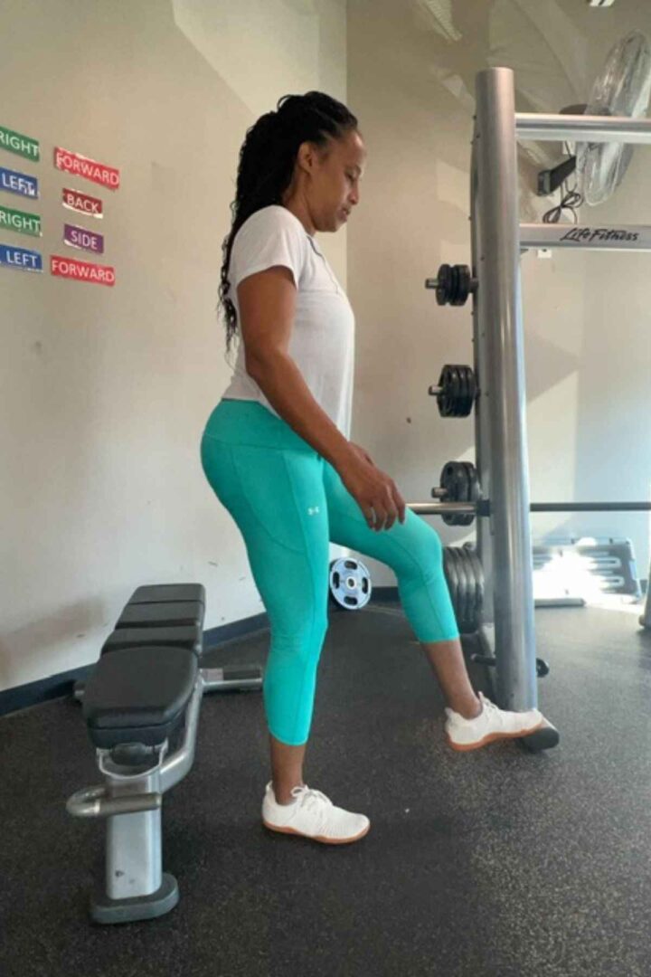 woman doing pistol squats near a weight bench