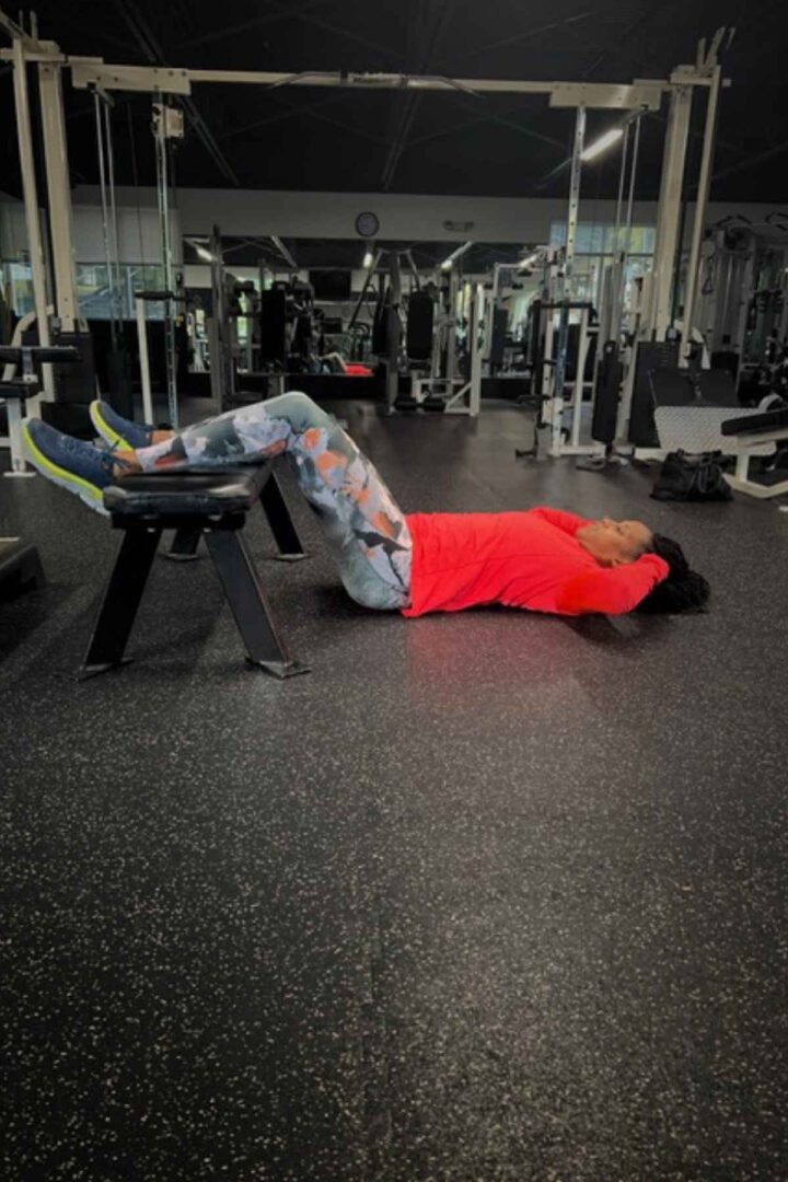 woman doing floor crunch for ab bench exercises with feet on the bench